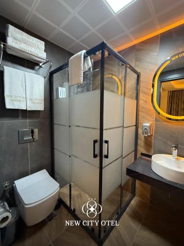 a bathroom with a shower and a toilet and a sink at New City Otel in Osmaniye
