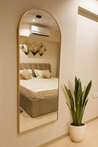 a mirror in a bedroom with a bed and a plant at Viento in Dehu Road