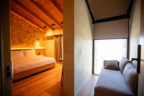 a bedroom with a bed and a couch and a window at Montis Agroturizëm Hotel Spa in Kaninë