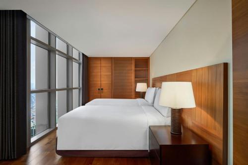 a bedroom with a white bed and a large window at JW Marriott Hotel & Suites Saigon, The Apartments in Ho Chi Minh City