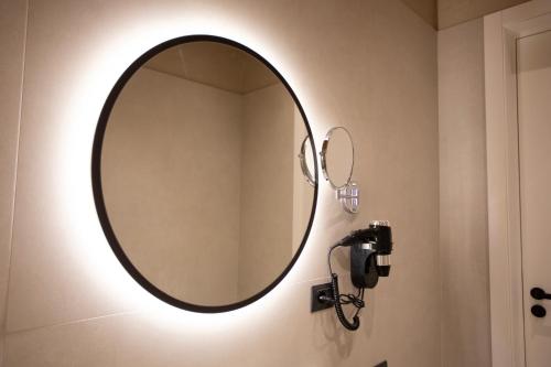 a bathroom mirror with a light on a wall at Montis Agroturizëm Hotel Spa in Kaninë