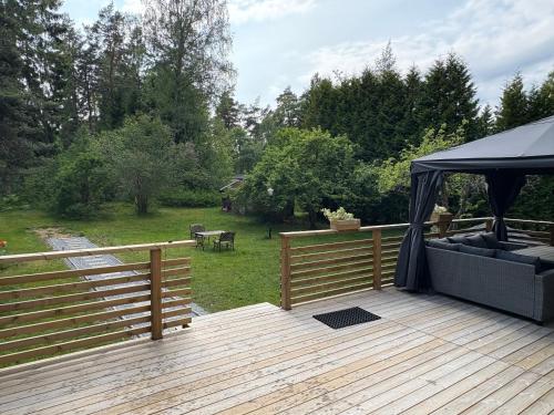a wooden deck with a gazebo and a yard at Röd Stuga by Falunio in Södertälje