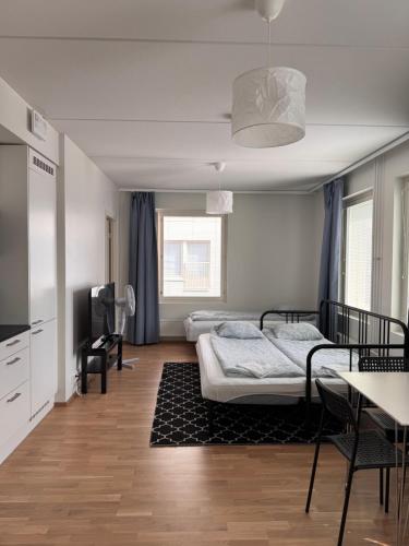 a bedroom with two beds and a desk and a tv at Transit Apartments HEL Airport in Vantaa