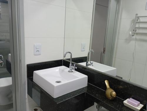 a bathroom with a white sink and a mirror at Apto 201 Familiar no centro do NB in Núcleo Bandeirante