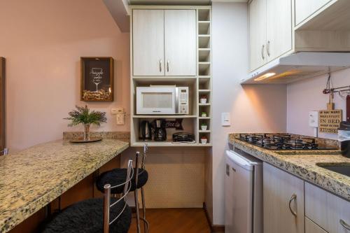 eine Küche mit weißen Schränken und einer Arbeitsplatte in der Unterkunft Rosa Edificio Morada das Hortêsias in Gramado
