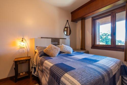 ein Schlafzimmer mit einem Bett mit einer blau-weißen Decke in der Unterkunft Rosa Edificio Morada das Hortêsias in Gramado