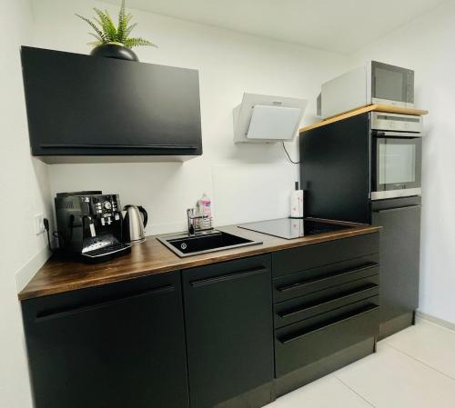 a kitchen with black cabinets and a black refrigerator at 90m2 Loft I Kaffee I Terrasse I E-Parkplatz I 65' Smart TV in Rosenheim