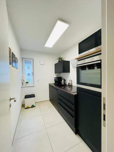 a kitchen with black cabinets and a large appliance at 90m2 Loft I Kaffee I Terrasse I E-Parkplatz I 65' Smart TV in Rosenheim