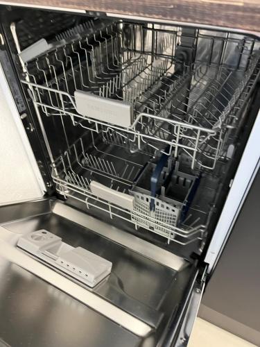 an open dishwasher with dishes inside of it at 90m2 Loft I Kaffee I Terrasse I E-Parkplatz I 65' Smart TV in Rosenheim