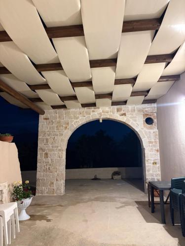 a room with a stone wall and a ceiling with a table at La casa di nonna Marta in Martina Franca