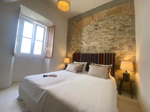 a bedroom with a large white bed with a stone wall at Casa Amanhada Apartamento Zero in Grândola