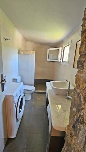 a bathroom with a washing machine and a sink at Lithos Haven in Agía Paraskeví