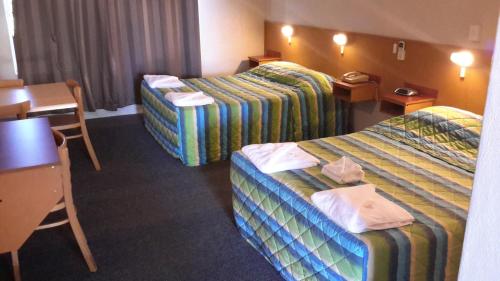 a hotel room with two beds and a table at Herbert Valley Motel in Ingham