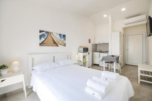 a white bedroom with a white bed and a kitchen at DIVA STUDIO PUNTA SKALA in Petrcane