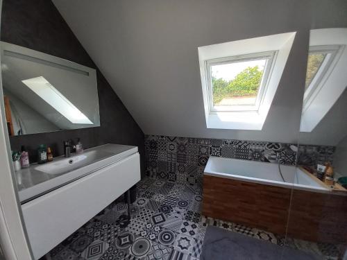 La salle de bains est pourvue d'un lavabo, d'une baignoire et d'une fenêtre. dans l'établissement Magnifique maison contemporaine piscine chauffée, à Crozon