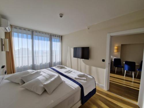 a bedroom with a large white bed with a tv on the wall at Batumi Aparthotel In Orbi City 2025 in Batumi