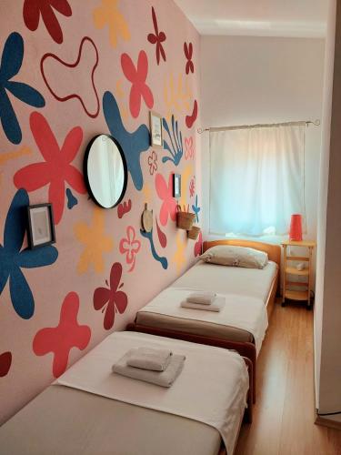 two beds in a room with flowers painted on the wall at Guest House Sandra in Tisno