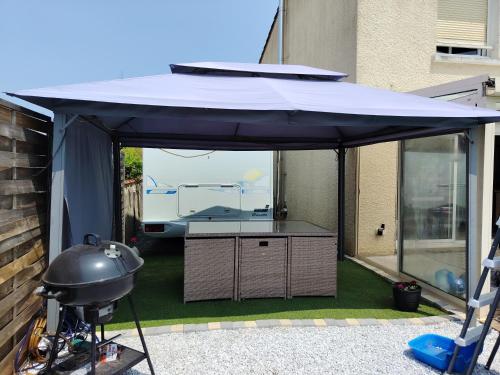 un parasol noir sur une terrasse avec un gril dans l'établissement Séjour insolite Camping-car fixe, à Marennes