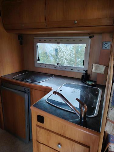 une cuisine avec un évier et une fenêtre dans un camping-car dans l'établissement Séjour insolite Camping-car fixe, à Marennes