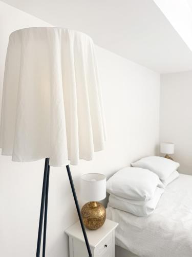 - une chambre blanche avec un lit et une lampe dans l'établissement L Écrin de Neuilly - La Défense & Champs Elysées 10 min away, à Neuilly-sur-Seine