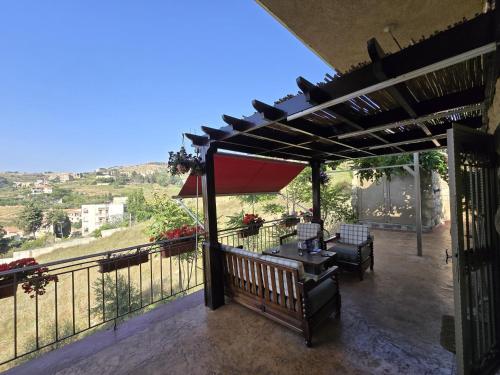 a patio with a bench and a table and umbrella at Maison des Couleurs in Aley