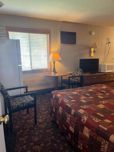 a bedroom with a bed and a table and a desk at Dakota Winds Motel in Kimball