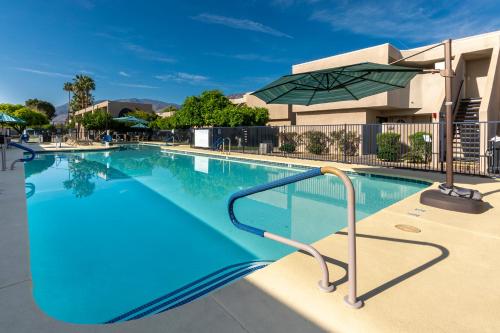 a swimming pool with an umbrella next to a building at Vista Mirage Resort in Palm Springs