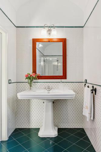 a bathroom with a white sink and a mirror at Palazzo Di Lorenzo - Exclusive Palace with Panoramic Terrace and Minipool in Noto