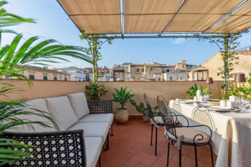 a patio with a couch and tables and chairs at Palazzo Di Lorenzo - Exclusive Palace with Panoramic Terrace and Minipool in Noto