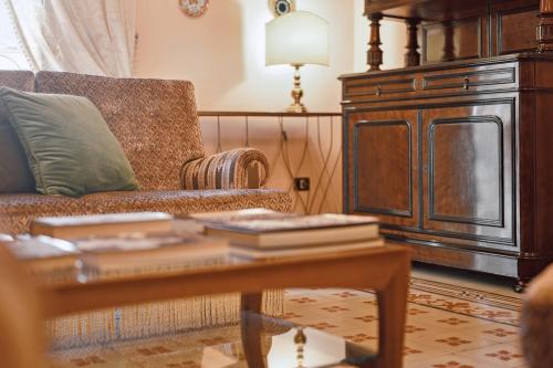 a living room with a couch and a table with books at Palazzo Di Lorenzo - Exclusive Palace with Panoramic Terrace and Minipool in Noto