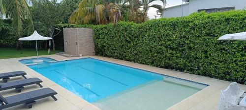 a swimming pool with two chairs and a hedge at Hermosa Casa Campestre en Ricaurte Girardot in Ricaurte