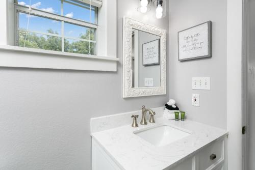 une salle de bain blanche avec un lavabo et un miroir dans l'établissement Main Street Retreat #14 - King Bed, On Main St, Shared Hot Tub & Pool, à Fredericksburg