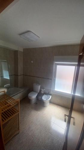 a bathroom with two toilets and a tub and a window at Casa O Castriño in Cambados