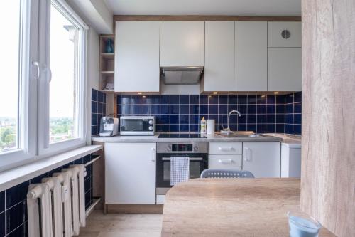 赫扎努夫New modern flat on the way from Kraków to Oświęcim的厨房配有白色橱柜和蓝色瓷砖