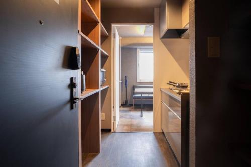 a hallway leading to a kitchen with wooden shelves at Pin pon hotel & cabin Tokuyama Ekimae - Vacation STAY 30945v in Shunan