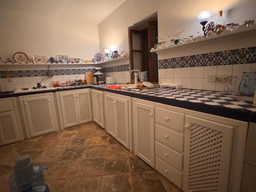 a kitchen with white cabinets and black and white tiles at A historic STONE VILLA with private garden, terrace and private pool just for you in Kliru