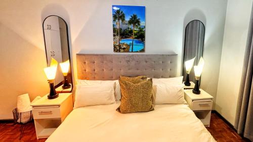 a bedroom with a bed with two lamps and two mirrors at HOPE-always in Cape Town