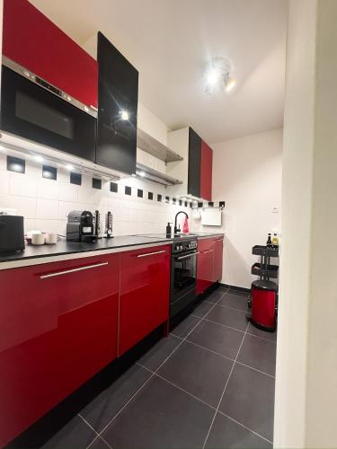 une cuisine avec armoires rouges et appareils noirs dans l'établissement L Écrin de Neuilly - La Défense & Champs Elysées 10 min away, à Neuilly-sur-Seine