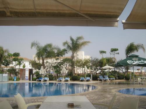 una piscina en un complejo con sillas y sombrillas en Polyxenia Isaak Luxury Villas and Apartments, en Protaras