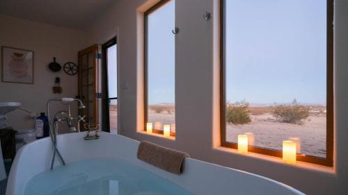 a bath tub in a bathroom with two windows at Desert's Edge in Hidden River