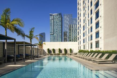 a swimming pool with chairs and palm trees in a city at Residence Inn by Marriott Los Angeles L.A. LIVE in Los Angeles