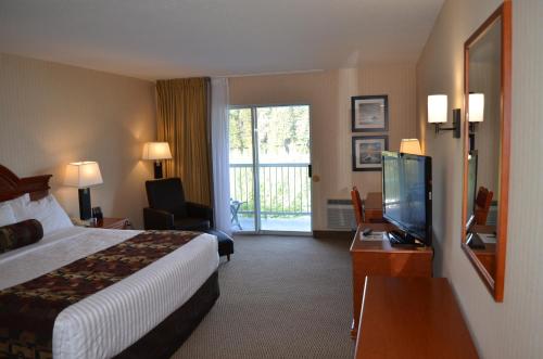 a hotel room with a bed and a flat screen tv at Inn on Long Lake in Nanaimo