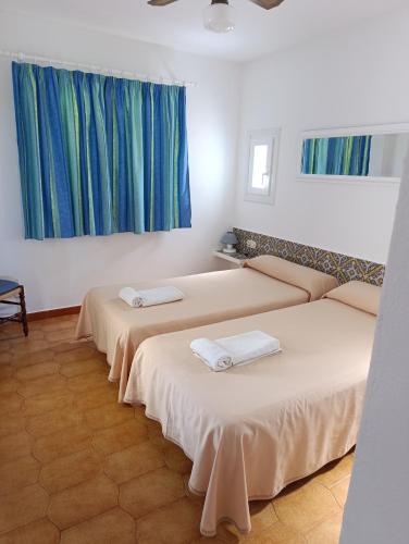 two beds in a room with blue curtains at Apartamento Ideal in Alaior