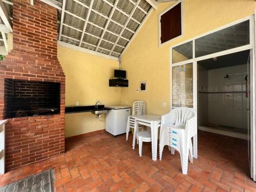 a patio with white chairs and a table and a fireplace at Recanto da montanha in Teresópolis