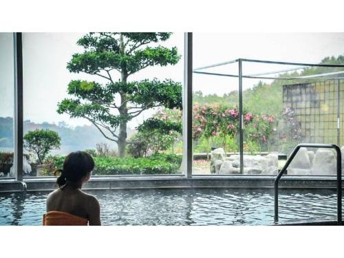 a woman sitting in a swimming pool looking at the water at Ouka no sato La-Foret Shobara - Vacation STAY 35116v in Shōbara