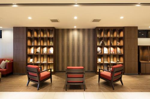 a lobby with two chairs and shelves of wine bottles at HOTEL MYSTAYS Kanazawa Castle in Kanazawa