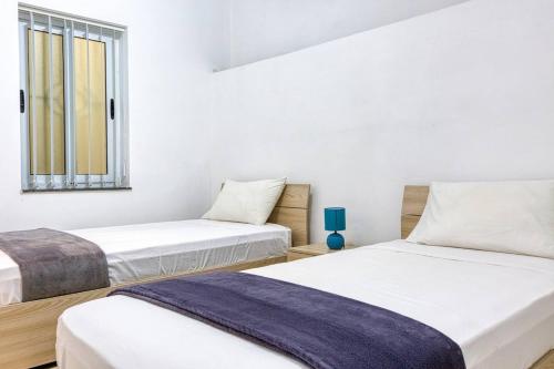 Dos camas en una habitación con paredes blancas y una ventana. en Modern 3 bedroom Maisonette in the heart of Swieqi, en Is-Swieqi
