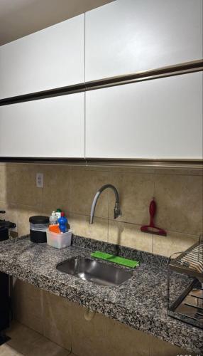 eine Küchentheke mit einer Spüle und weißen Schränken in der Unterkunft Apartmento São João in Campina Grande