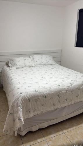 ein Schlafzimmer mit einem Bett mit einer weißen Tagesdecke in der Unterkunft Apartmento São João in Campina Grande