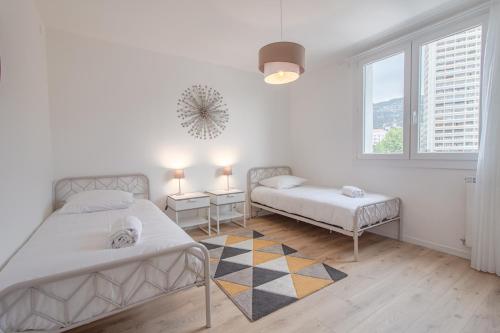 une chambre blanche avec deux lits et une fenêtre dans l'établissement Appartement T3 climatisé, cœur de Toulon, à Toulon